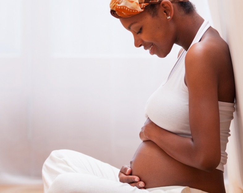 pregnant woman smiling as she cradles baby