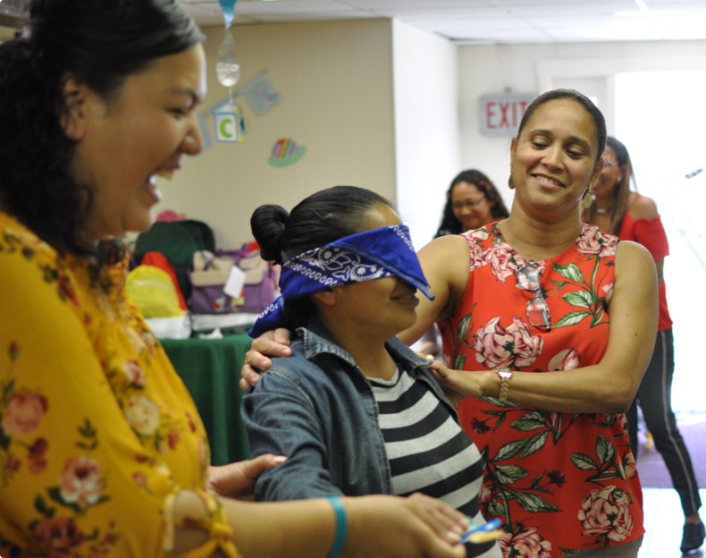 Women moving blindfolded woman to activity